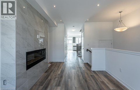 A spacious hallway with a fireplace and wood flooring.