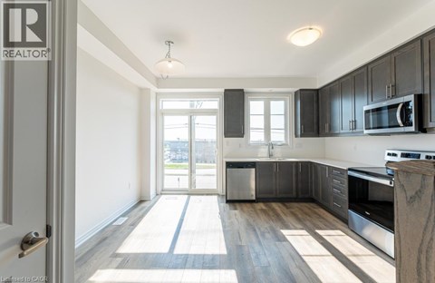 A well-lit kitchen with dark wood cabinets and a white door.