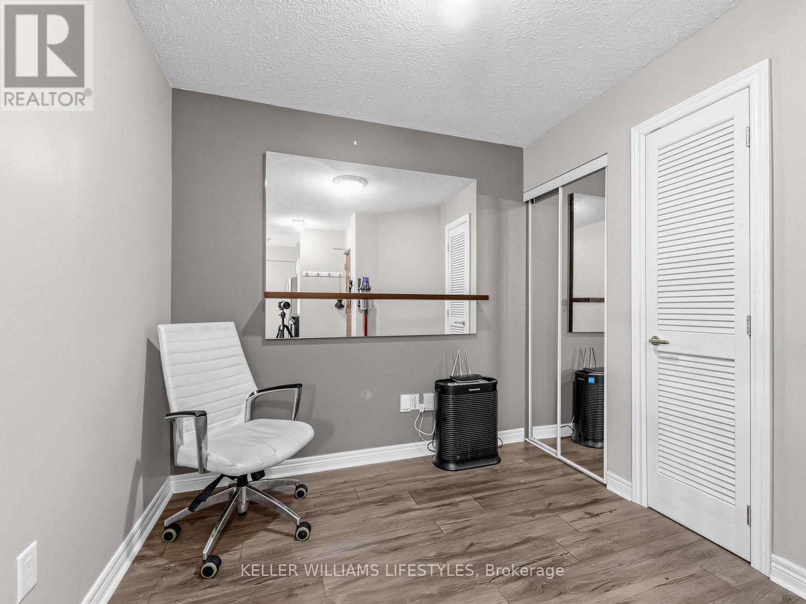 A room with a chair, mirror, and two air conditioners.