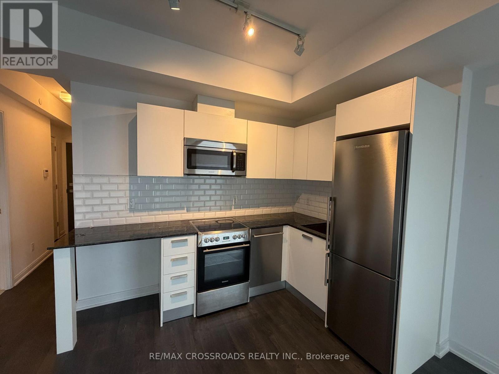 A kitchen with a refrigerator, oven, and microwave.