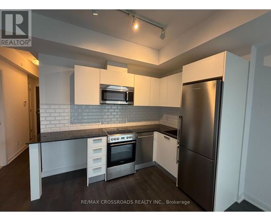 A kitchen with a refrigerator, oven, and microwave.