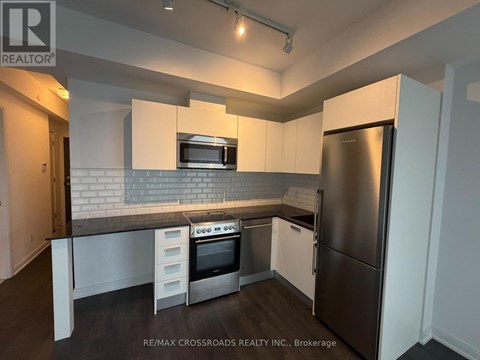 A kitchen with a refrigerator, oven, and microwave.