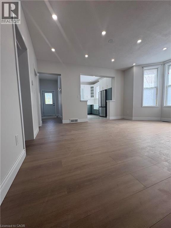 A spacious room with wooden flooring and a door on the left side.