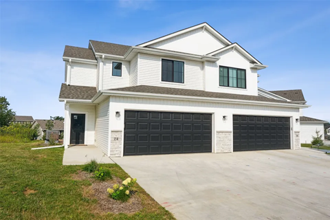 A two-story house with a white exterior and black garage doors.