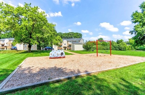 A playground with a slide and swing set in a grassy area.