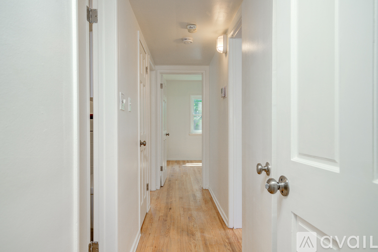 A hallway with white doors and a wooden floor.