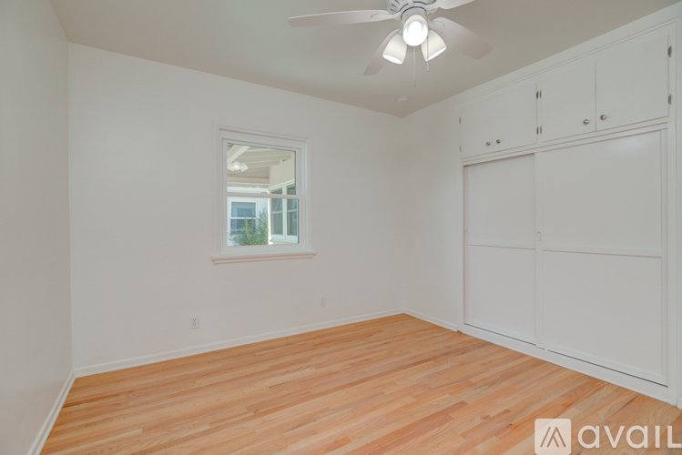 A room with a ceiling fan and wooden flooring.