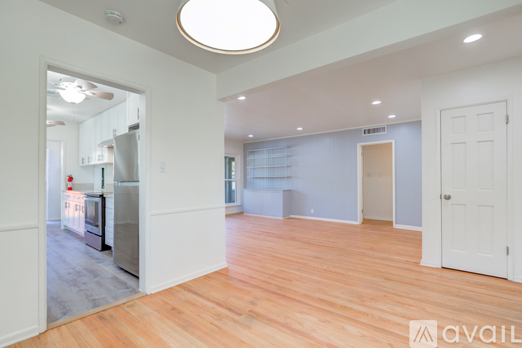 A spacious room with wooden floors and a large window.