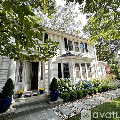 A white house with a front porch and a garden.