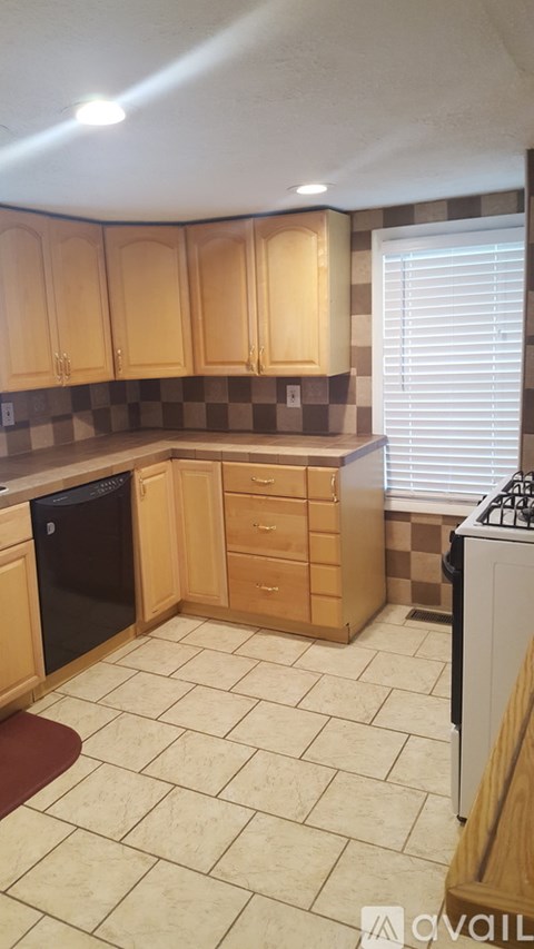 A kitchen with wooden cabinets and a black dishwasher.
