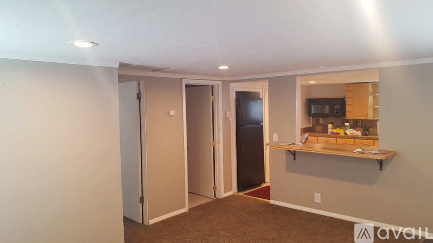 A room with a white door, a black door, and a counter with a microwave on it.