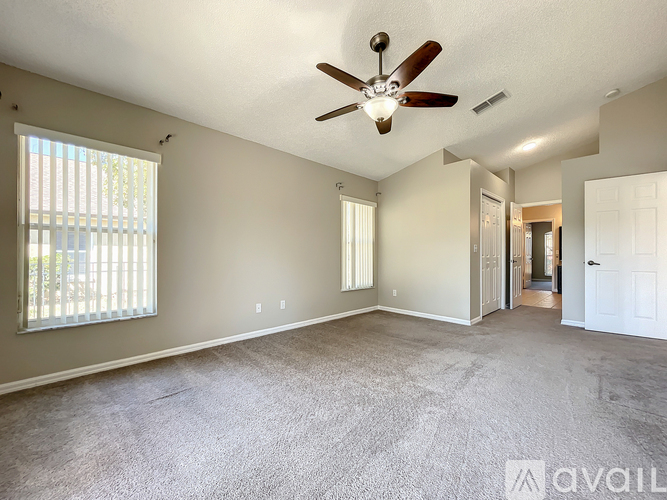 A spacious room with a ceiling fan and carpeted floor.