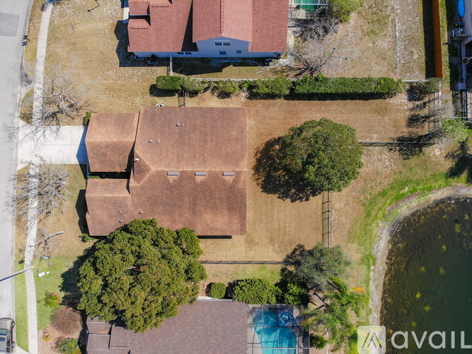 A bird's eye view of a residential area with houses, trees, and a pool.