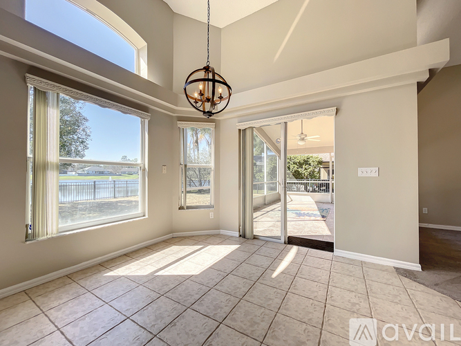 A room with a large window and a view of a fence and trees outside.