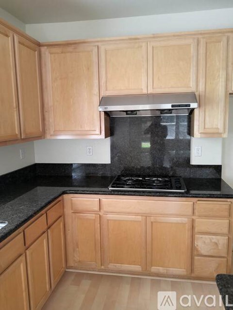 A kitchen with wooden cabinets and a black countertop.