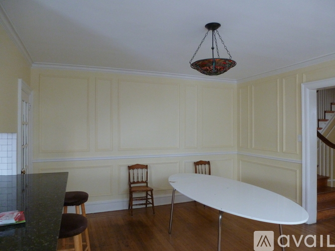 A dining room with a table, chairs and a hanging light fixture.