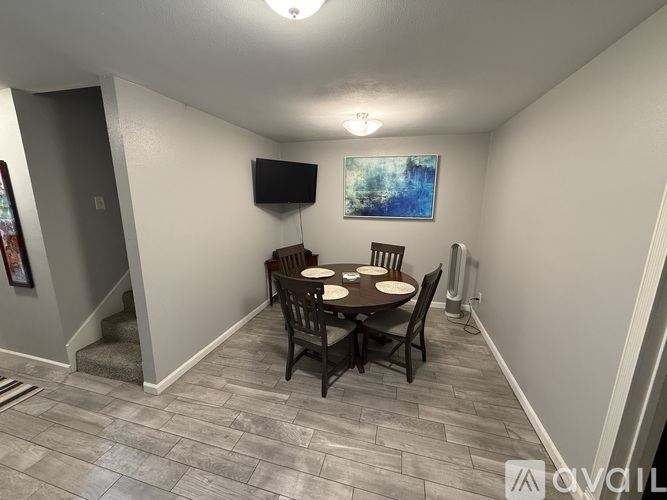 A dining area with a table and chairs and a television on the wall.