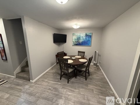 A dining area with a table and chairs and a television on the wall.
