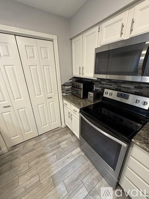 A kitchen with white cabinets and a black stove top oven.