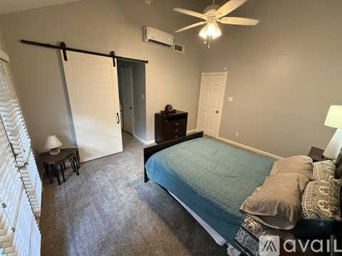 A bedroom with a bed, dresser, and sliding door.