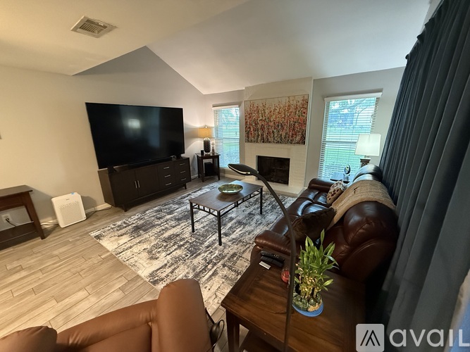 A living room with a brown leather couch and a black television.