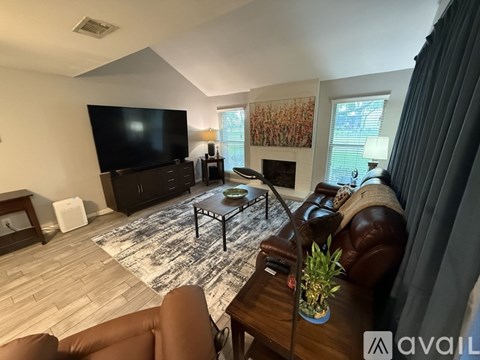 A living room with a brown leather couch and a black television.