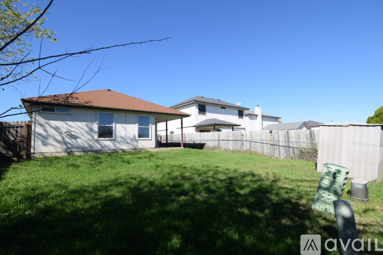A house with a brown roof and a white fence is surrounded by green grass.