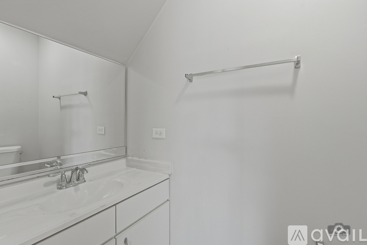 A white bathroom with a sink, mirror, and towel bar.