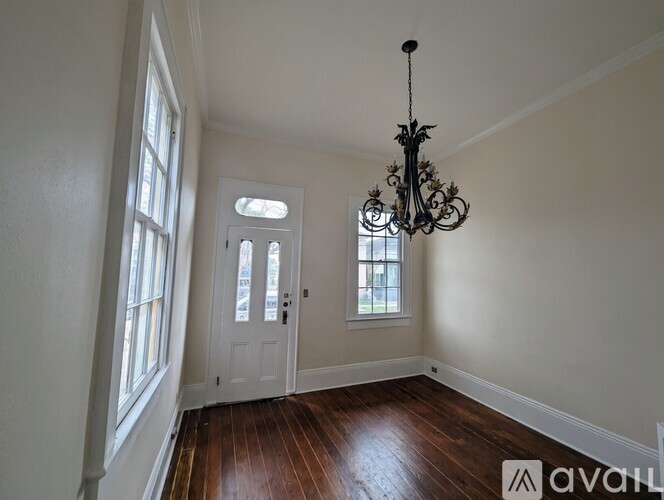 A room with a chandelier, a door, and a window.