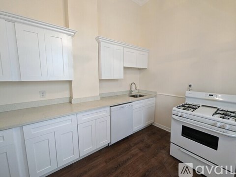 A kitchen with white cabinets and a white stove.