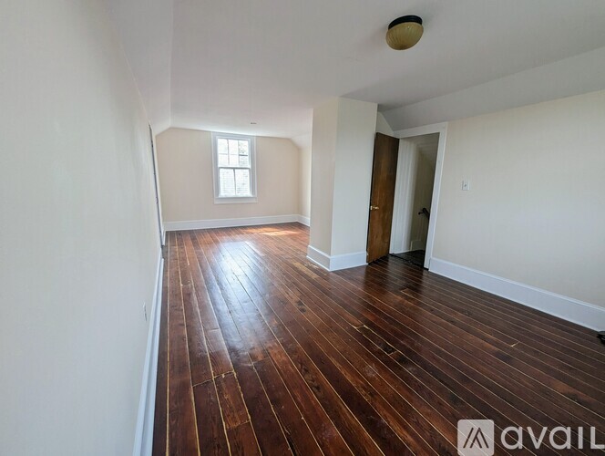 A room with wooden flooring and a window.
