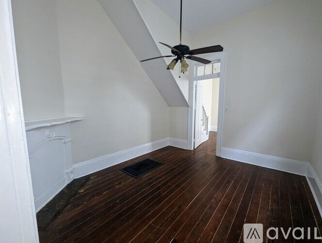A room with a ceiling fan and wooden flooring.