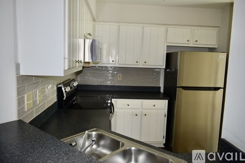 A kitchen with a black counter top and white cabinets.
