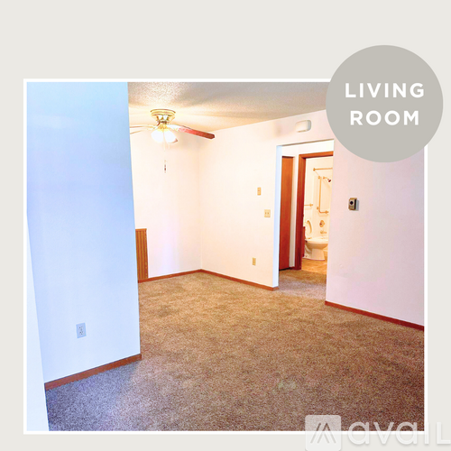 A living room with a carpeted floor and a ceiling fan.