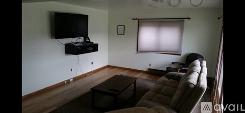 A living room with a brown couch and a flat screen TV mounted on the wall.