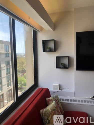 A living room with a red couch and a flat screen TV mounted on the wall.