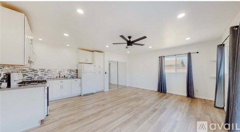 A spacious kitchen with white cabinets and a ceiling fan.