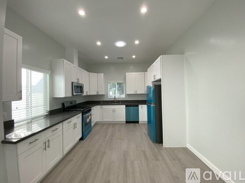 A modern kitchen with white cabinets and a blue island.