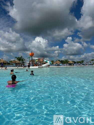 People are swimming in a pool with a cloudy sky in the background.