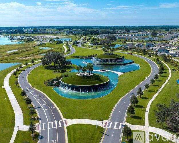 A beautiful aerial view of a roundabout with a fountain in the center, surrounded by a grassy area and roads.