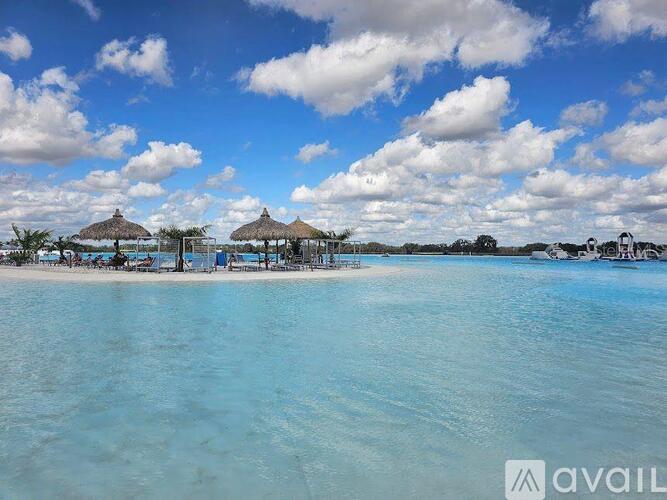 A beach with clear blue water and a few umbrellas.