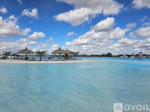 A beach with clear blue water and a few umbrellas.