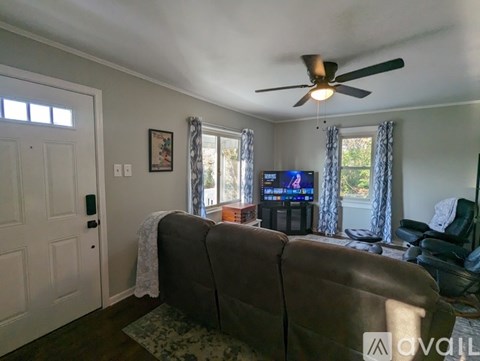 A living room with a grey couch and a ceiling fan.