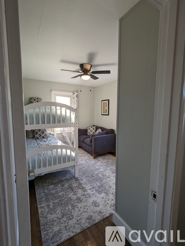 A bedroom with a white bed and a ceiling fan.
