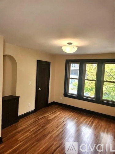 A room with wooden floors and a window showing greenery outside.