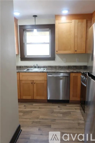 A kitchen with wooden cabinets and a window above the sink.