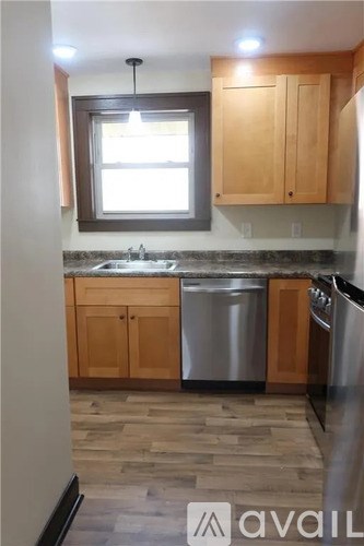 A kitchen with wooden cabinets and a window above the sink.
