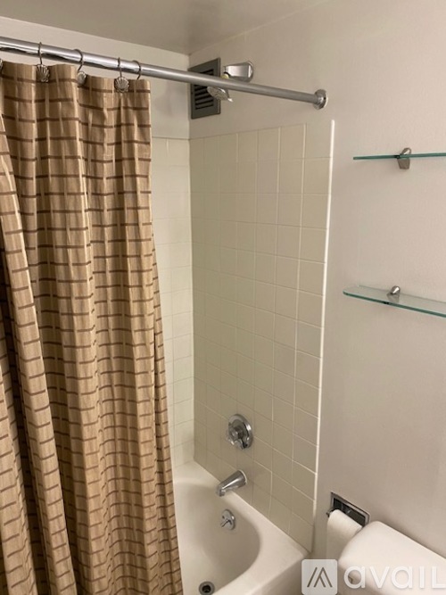 A shower area with a brown shower curtain and a white tub.