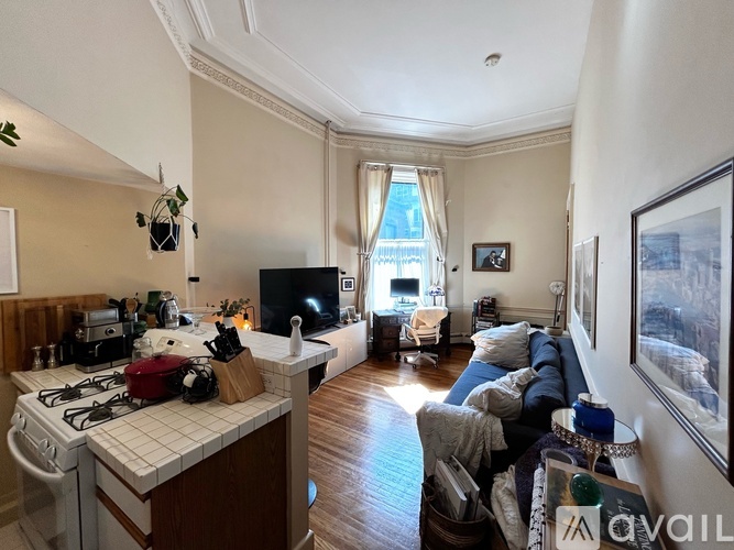 A living room with a couch and a kitchen area with a stove.