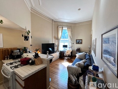 A living room with a couch and a kitchen area with a stove.